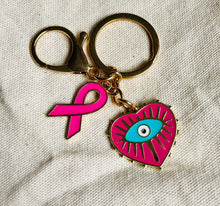 Charger l&#39;image dans la galerie, Porte clé bijou de sac octobre rose en acier inoxydable doré à l’or fin coeur avec un œil et ruban rose vif
