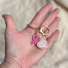 Charger l&#39;image dans la galerie, Porte clé bijou de sac octobre rose en acier inoxydable doré à l’or fin coeur avec un œil et ruban rose vif
